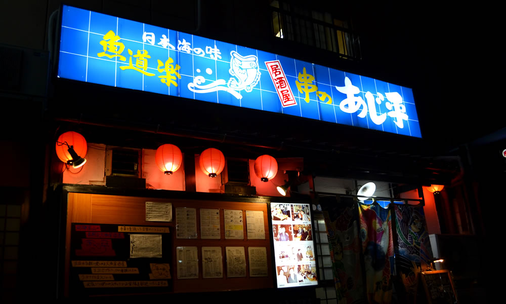 A Showa-era look with a blue sign, red lanterns and a naked light bulb
